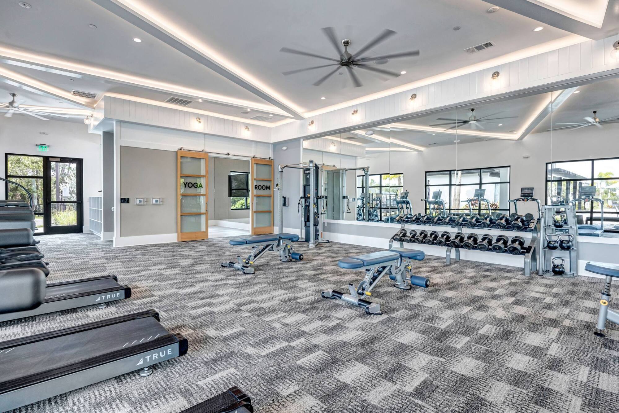 Fitness center and yoga room at Avasa Hammock Landing in West Melbourne, FL with mirrored walls, training benches, and free weights.
