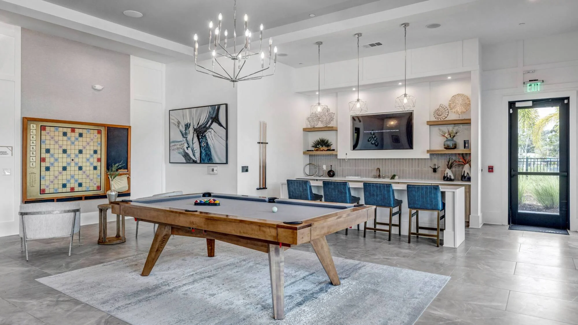 Resident game room at Avasa Hammock Landing in West Melbourne, FL with a pool table, chandelier, and clubhouse bar seating.