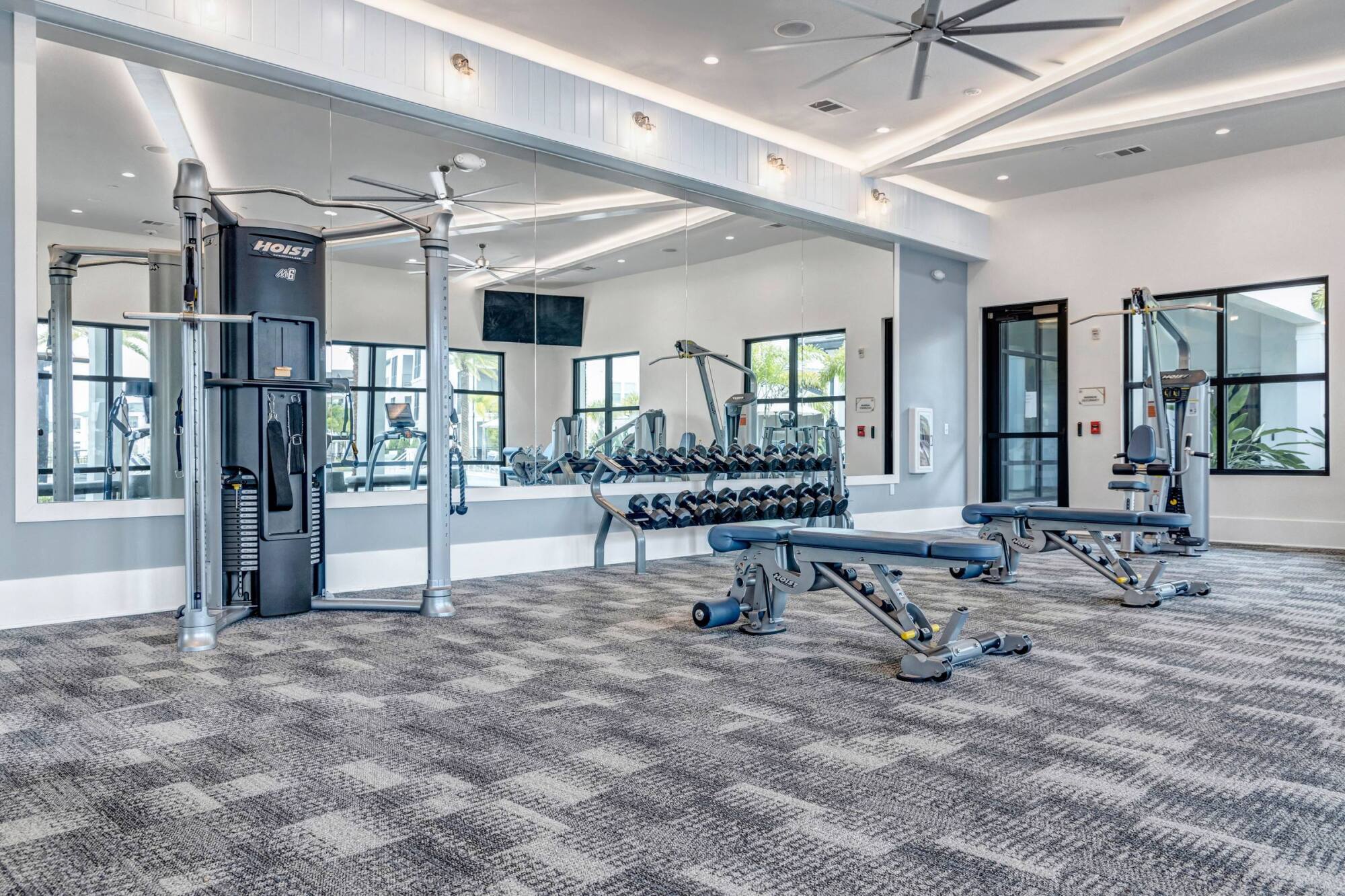 Strength training area at Avasa Hammock Landing in West Melbourne, FL with weight machines, dumbbells, and mirrored walls.