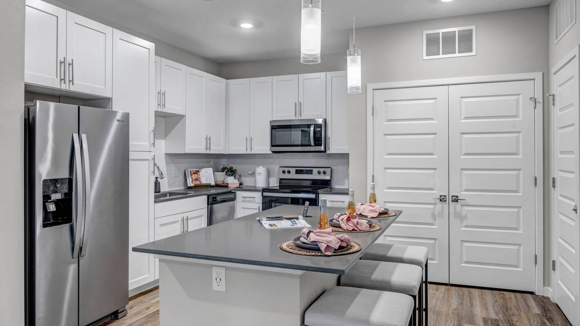 Apartment kitchen at Avasa Hammock Landing in West Melbourne, FL with a quartz island, bar seating, and stainless steel appliances.