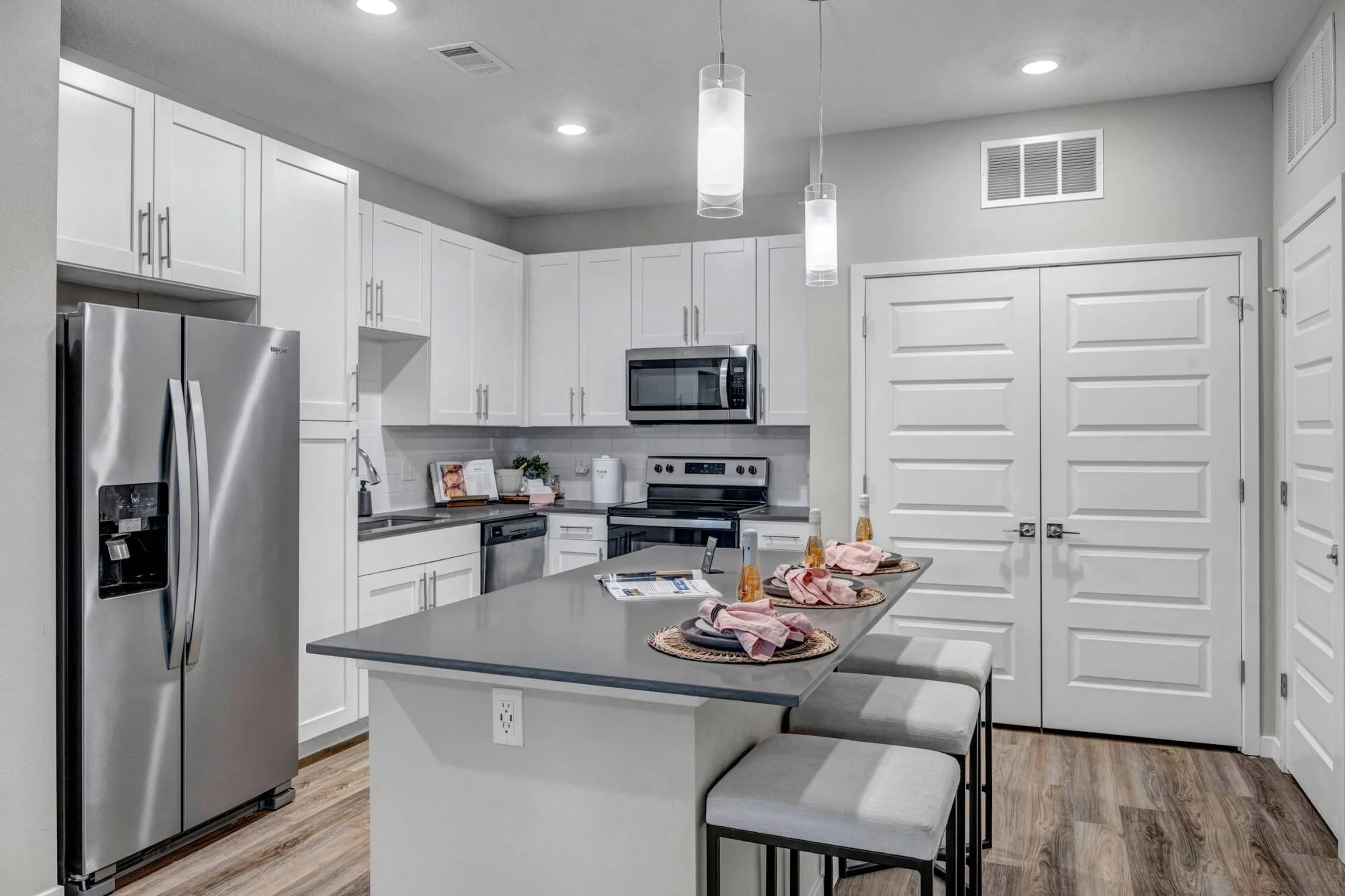 Kitchen at Avasa Hammock Landing in West Melbourne, FL with pendant lighting over a quartz island and stainless steel appliances.